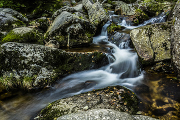 Naklejka na ściany i meble Waterfall falling on stones through autumn forest. Fall nature specification.