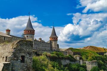 Fototapeta na wymiar Old Kamianets-Podilskyi Castle under a cloudy blue sky. The fortress located among the picturesque nature in the historic city of Kamianets-Podilskyi, Ukraine
