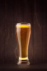 Weizen beer glass with golden sparkling lager on dark wood board. Template for advertising, design, branding identity, restaurant menu, cover.