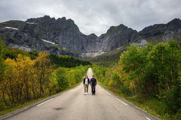 Friends walk on a scenic road on Lofoten islands in Norway