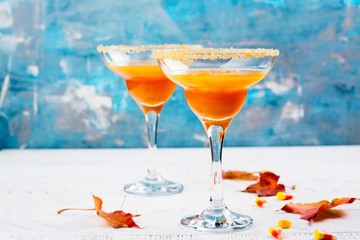 Autumn pumpkin martini cocktail with halloween decor on wooden table. Copy space