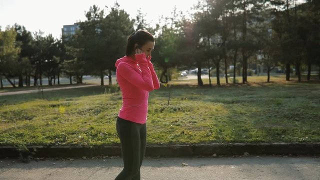 Pretty sportswoman in pink sportswear jogging outdoors, healthy lifestyle concept. Slow motion.