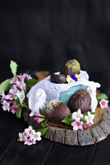 Easter sweets. home made chocolate. chocolate eggs. pink bloom flowers. on a black background. dark photo