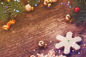 christmas gingerbread snowflake cookies with evergreen twigs frame with copy space on wood, retro toned