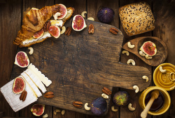 breakfast. a croissant with figs and honey. brie cheese and nuts. wooden board. Vintage background. brown photo. family breakfast. homemade baking