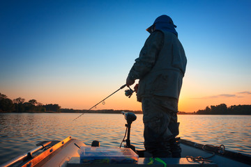 A fisherman fishing in a lake at sunset