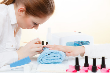 Beautician preparing nails before manicure, pushing back cuticles