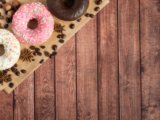 Donuts lie on the paper coffee beans on wooden rustic background