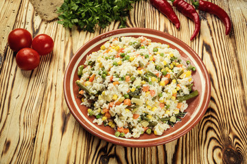 Colorful rice and vegetable salad,Bowl of pasta (orzo)or rice with vegetables, selective focus,Appetizing healthy rice with vegetables in plate on a wooden background,Delicious risotto with vegetables