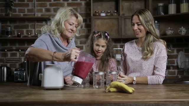 Grandmother pouring berry smoothie into mason jars