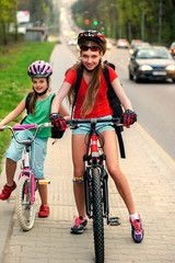 Bikes bicyclist girl. Girls wearing bicycle helmet with rucksack ciclyng bicycle. Bike share program save money and time at city street. Children travel unaccompanied.