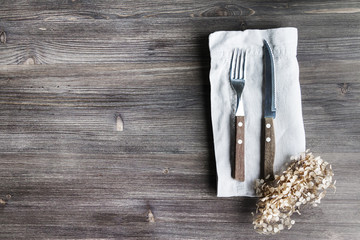 Concept of simple organic food - laconic design cutlery set on rustic wooden table and linen tissue. Top view. Copy space..