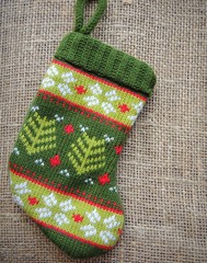 Christmas knitted mini sock with winter ornament on burlap background.