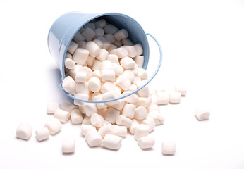Fluffy white marshmallow macro in blue bucket isolated over white background. Heap of white marshmallows. Food background. Copy space.