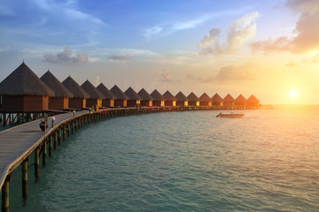 Fototapeta premium houses over the transparent quiet sea water on a sunset. Maldives..