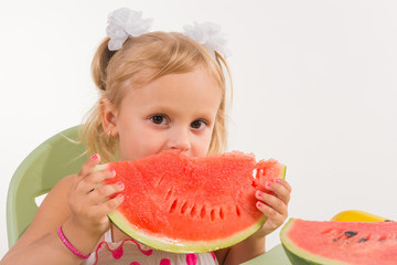 A child, a little girl, appetizingly eats a juicy watermelon.