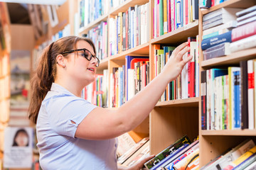 Woman in bookstore or library looking for book