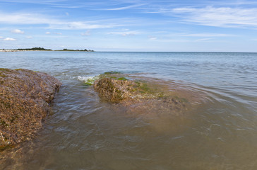 sunny day with Waves hitting stones on the beach