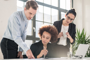 Young female employee asking for advice her helpful experienced colleagues in the office