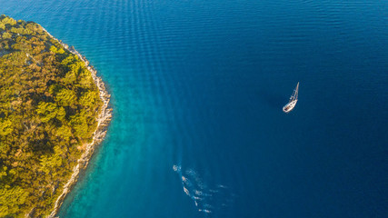 Aerial view of sailing boat anchoring next to reef