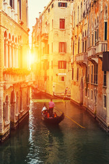 Venetian gondolier punting gondola in water canal with green water