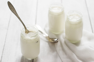 Homemade yogurt in a glass jar on a wooden table. Rustic style, selective focus.