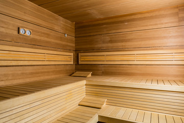 Interior of an empty dry sauna with brown wooden walls and benches in a modern hotel or in a spa and wellness center 