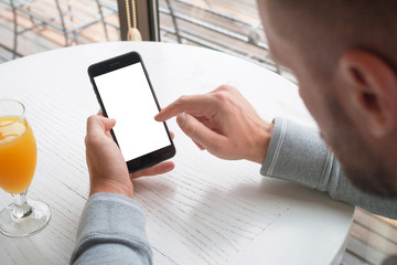Touch mobile phone screen with right hand. Isolated white screen for mockup. Clean white wooden desk in background.
