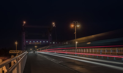 Fototapeta na wymiar Autos und Bahn auf nächtlicher Brücke