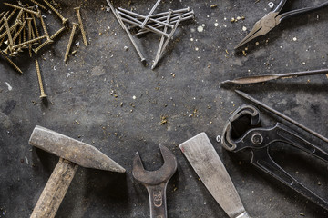 Different hand tools, nails and screws on dark metal background