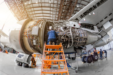 Specialist mechanic repairs the maintenance of a large engine of a passenger aircraft in a hangar. - obrazy, fototapety, plakaty