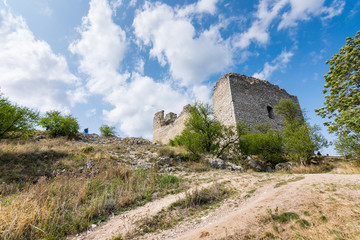 Fototapeta na wymiar Castle ruin on the hill, blue sky and white clouds, path on the ground