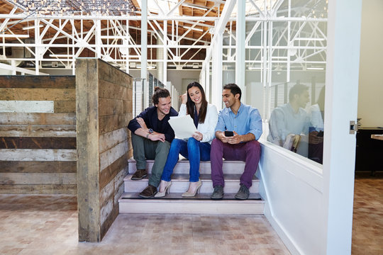 Millennial business people sitting on stairs for a meeting