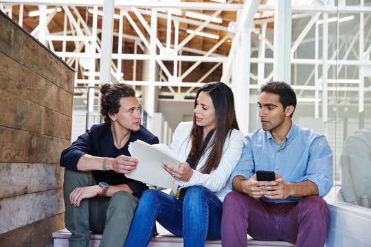 Millennial business people sitting on stairs for a meeting