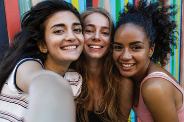 Happy friends taking a selfie. Three smiling women looking at camera on a mobile phone.