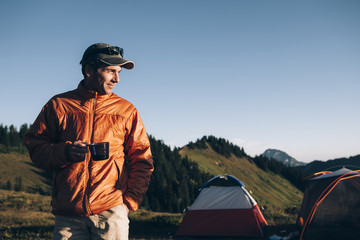 Portarit of man camping in mountains, holding cup