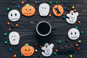 A cup of coffee with colors candy and scary gingerbreads on the Halloween.