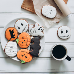 Preparation for Halloween. Coffee and scary gingerbread cookies on a wooden background.