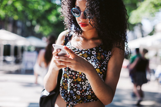 Latin woman using her smartphone on the street.