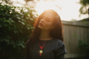 Pretty dark haired woman in alleyway with sunburst light at sunset