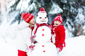 Naklejka na ściany i meble Kids building snowman. Children in snow. Winter fun.
