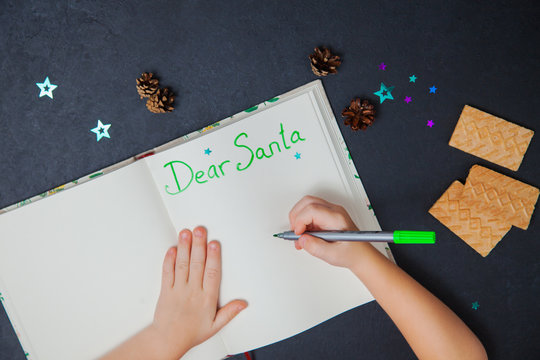 Little Child Writing Letter To Santa Claus On A Blank Sheet Of Paper