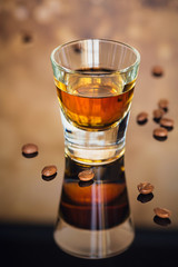 Cognac or liqueur, coffee beans and spices on a glass table.