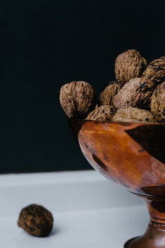 copper bowl with walnuts against a dark background