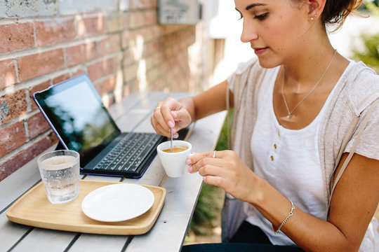 A woman sitting outdoors with a smart tablet & coffee