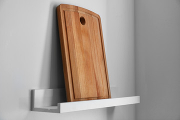 Wooden cutting board on shelf in kitchen