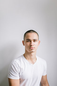 Handsome young man portrait in white t-shirt in front the white wall