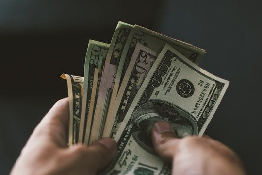 Close-up of a hands counting a stack of US dollar bills