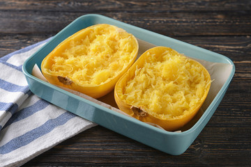 Baking dish with cut spaghetti squash on wooden background