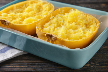 Baking dish with cut spaghetti squash on wooden background